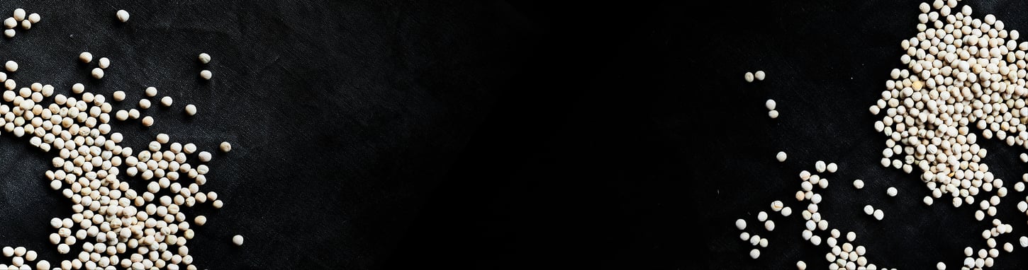 The image displays white peas scattered across a black background. The peas are clustered into two main groups, with one group more densely packed than the other.